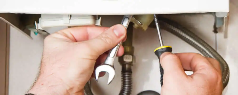 Boiler repair technician tightening pipe fittings and connections in Bakersfield, CA