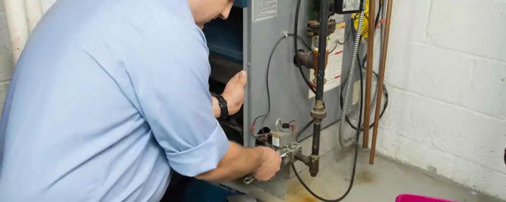 Furnace repair technician inspecting and servicing a home heating system in Bakersfield, CA