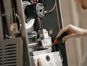 Furnace repair technician inspecting internal components and wiring in Bakersfield, CA