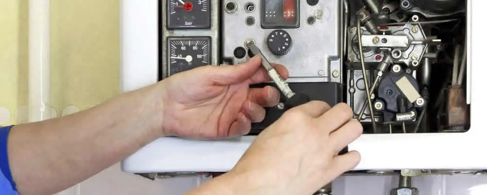 Heating repair technician adjusting boiler controls and components in Bakersfield, CA