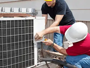 HVAC technicians repairing an outdoor AC unit on a rooftop in Bakersfield, CA