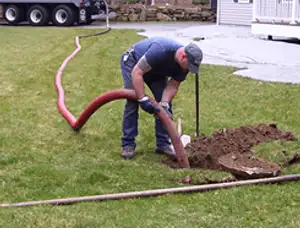 Septic pumping technician servicing a residential septic tank with a vacuum hose in Bakersfield, CA