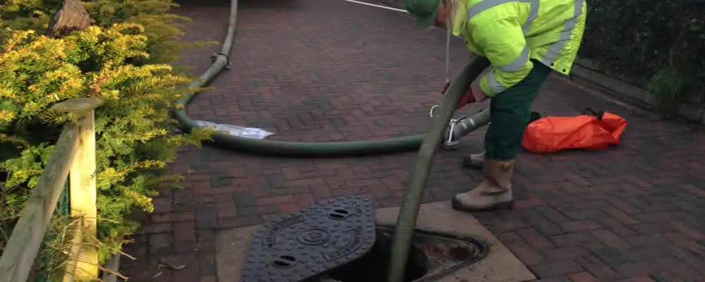 Septic tank cleaning technician servicing a septic tank with a vacuum hose in Bakersfield, CA