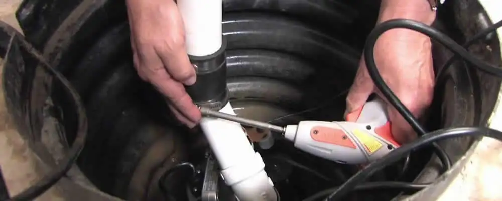 Sump pump installation technician connecting PVC discharge piping in Bakersfield, CA
