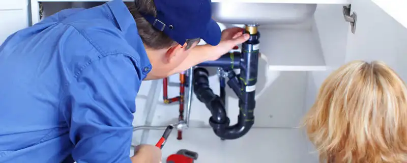 Plumber repairing under-sink drain pipes and fittings in Bakersfield, CA